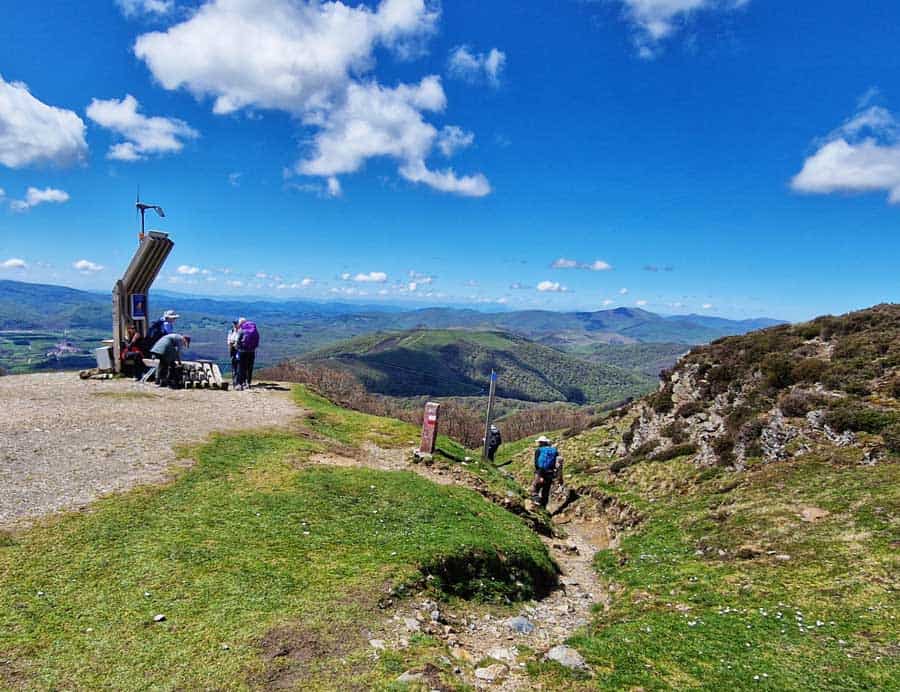 view of pilgrims arriving and leaving the highest point of the Napoleon Route on the Camino