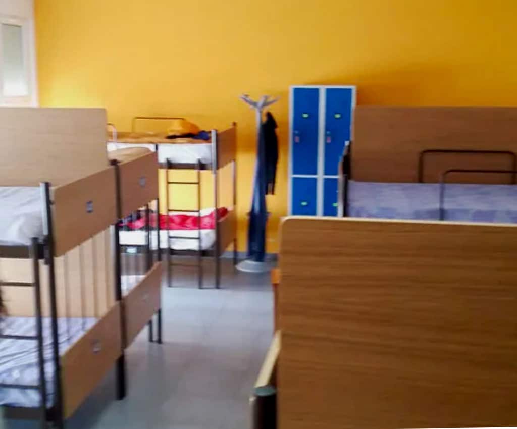 large pilgrim dormitory with bunk beds spaced our and with privacy screens