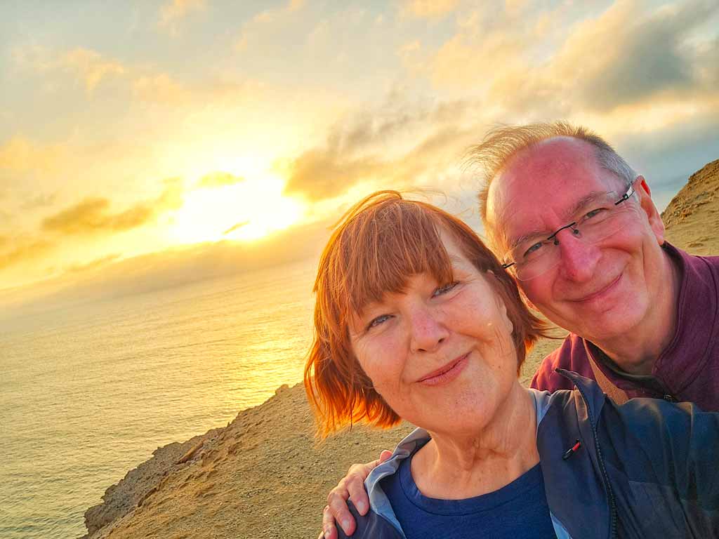colleen and gerry on the cliffs and dunes with the sun almost setting into the pacific ocean