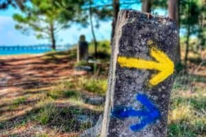 blue and yellow arrows on the Camino beside a  beach on the Spiritual Variant