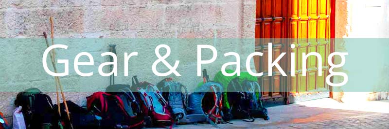 rucksacks in a row at an albergue with a banner saying gear and packing